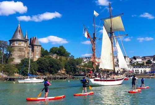 a group of people on paddle boards in the water with a sail boat at La Villa Préfaillaise in Préfailles