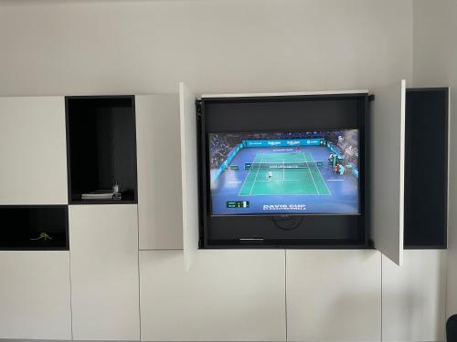 een tv aan de muur met een tennisspel erop bij Cofa'sea designvol appartement in Knokke-Heist