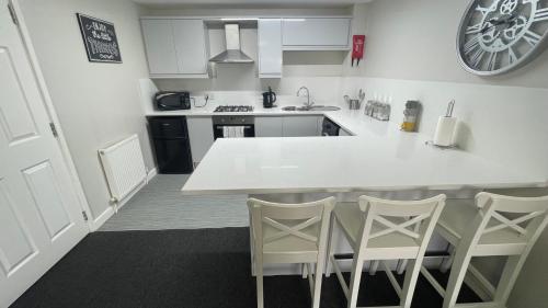 a kitchen with a white counter and chairs in it at Hosted By Ryan - 1 Bedroom Apartment in Liverpool