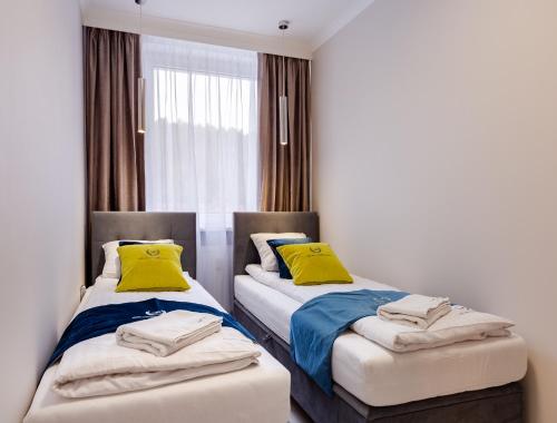 2 camas en una habitación con almohadas amarillas en ApartamentyGdansk eu Mieszkanie Przylesie, en Sopot