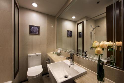 a bathroom with a toilet, sink, and mirror at Rosedale Hotel Hong Kong in Hong Kong