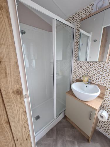 a bathroom with a shower and a sink and a mirror at Stunning Platinum Caravan in Rhyl 2 mins to Beach in Rhyl