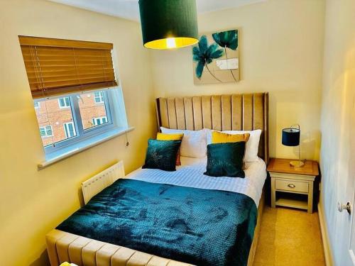 a bedroom with a bed with a blue blanket and a window at Spacious & modern 3 bedroom house in Peterlee in Wingate