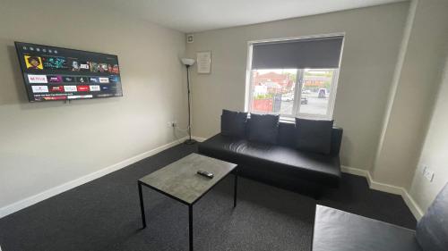 a living room with a black couch and a table at Hosted By Ryan - 1 Bedroom Apartment in Liverpool