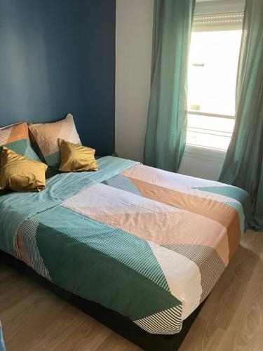 Cette chambre comprend un lit avec des draps colorés et une fenêtre. dans l'établissement Suite Royale stade de France, à Saint-Denis