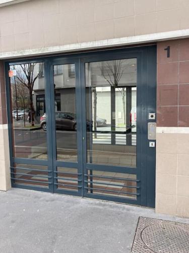 un bâtiment avec des portes bleues reflétant une rue dans l'établissement Suite Royale stade de France, à Saint-Denis