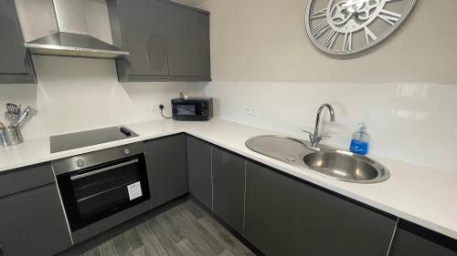 a kitchen with a sink and a clock on the wall at Hosted By Ryan - 2 Bedroom Apartment in Liverpool