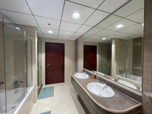La salle de bains est pourvue de 2 lavabos et d'un grand miroir. dans l'établissement Beachfront paradise just minutes from Dubai, à Ajman