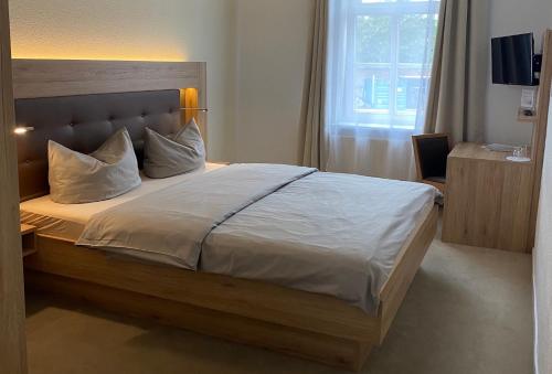 a bedroom with a large bed with white sheets and pillows at Pension Zum Alten Fährhaus in Rostock