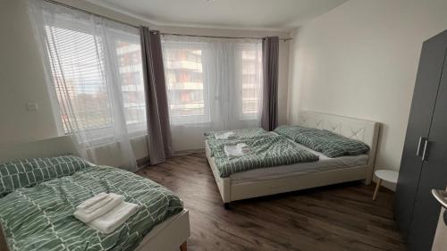 a small bedroom with two beds and two windows at Air-conditioned, 2 room Apartment with balcony, new building Rača in Bratislava