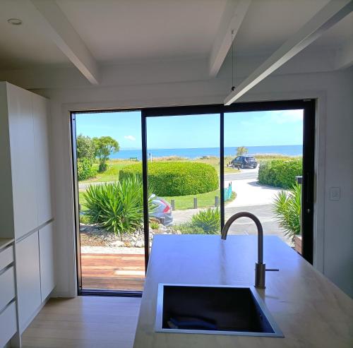 a kitchen with a sink and a view of the ocean at Pohara's Seaside Accommodation in Pohara