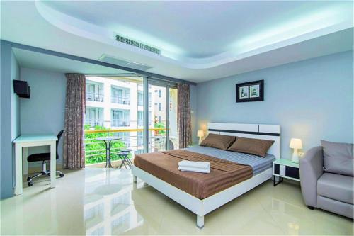 a bedroom with a bed and a chair and a balcony at First Hua Hin - Ji Ya in Hua Hin