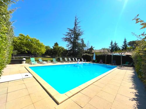 une grande piscine bleue avec des chaises et des arbres dans l'établissement Les Gîtes du Petit Mas, à Lagamas
