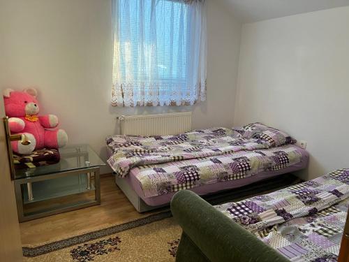 een kleine slaapkamer met 2 bedden en een teddybeer bij Apartmani Piramida Mjeseca i Sunca in Visoko