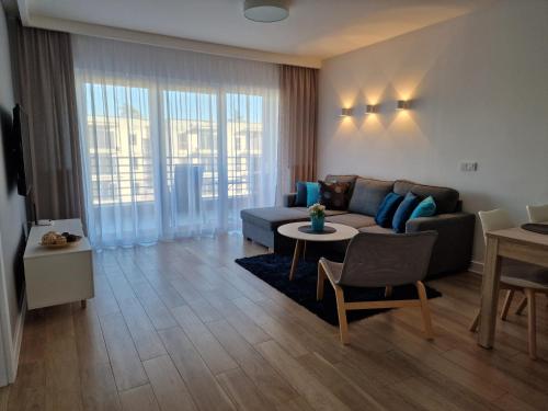 a living room with a couch and a table at Apartament Baltic Park - BEL MARE in Pogorzelica