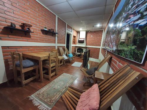 Habitación con mesa, sillas y pared de ladrillo. en Hostal Las Veraneras Ataco en Concepción de Ataco