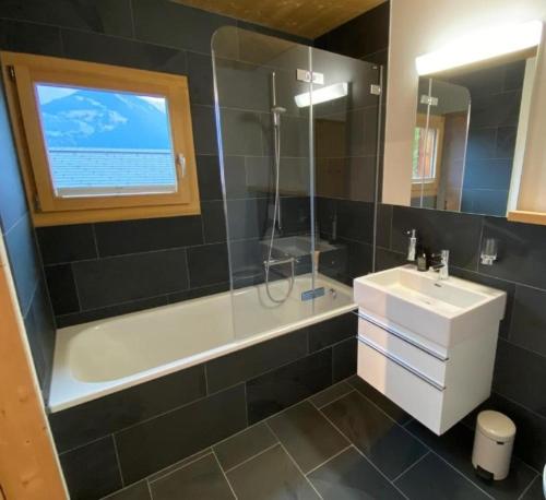 a bathroom with a tub and a sink and a shower at Ferienhaus Lumnezia Lux in Cumbels