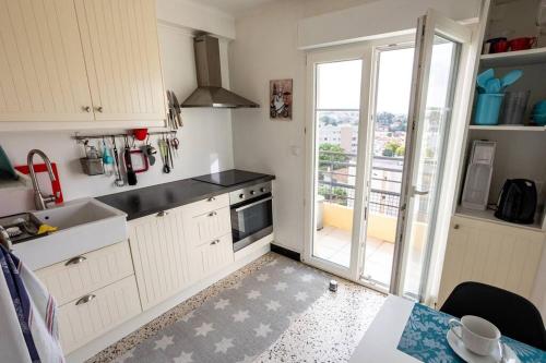 une cuisine avec des placards blancs et une grande fenêtre dans l'établissement Two bedroom in Antibes, à Antibes