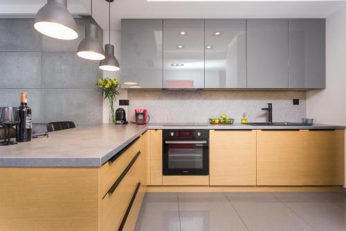 a kitchen with white and wooden cabinets and appliances at InPoint Central Apartments in Kraków