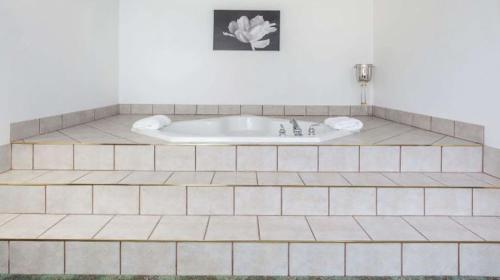 uma banheira na casa de banho com piso em azulejo em Best Stay Inn em Melville