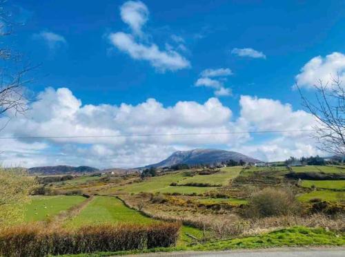 a green hillside with a blue sky and clouds at Teach Dunmore in the heart of Donegal Gaeltacht. in Falcarragh