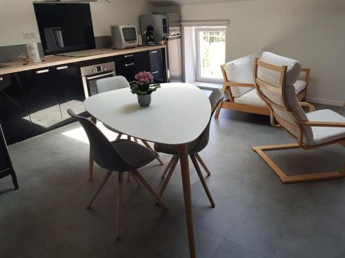 ein Wohnzimmer mit einem weißen Tisch und Stühlen in der Unterkunft Petite maison type Loft en plein bourg d'Ambazac in Ambazac