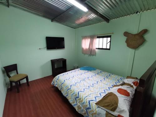 Hostal de la montaña ecoturismo في Mocoa: غرفة نوم بسرير وتلفزيون بشاشة مسطحة