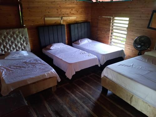 three beds in a room with wooden walls at MIRADOR DE BARU in Cartagena de Indias