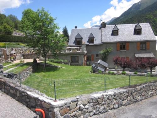 a large house with a stone fence in front of it at Marmotte Gîte 2à4 personnes avec cheminée à 10mn des pistes in Aragnouet