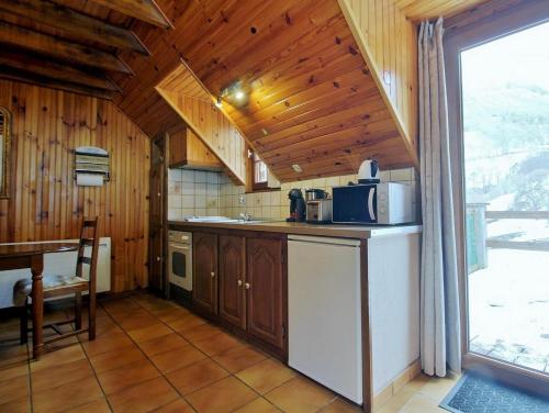 kuchnia z drewnianymi ścianami i stołem z kuchenką mikrofalową w obiekcie Marmotte Gîte 2à4 personnes avec cheminée à 10mn des pistes w mieście Aragnouet