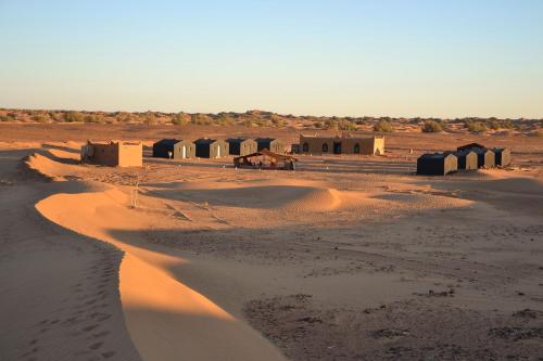 a desert with a group of huts in the sand at Camp Mbark authentic in Mhamid