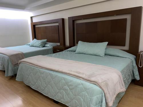two beds in a hotel room with two beds at Hotel & Suites Victoria in San Luis Potosí