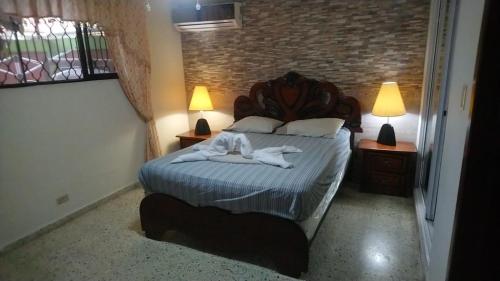 1 dormitorio con 1 cama con toallas en Guest-House alquiler en Santo Domingo