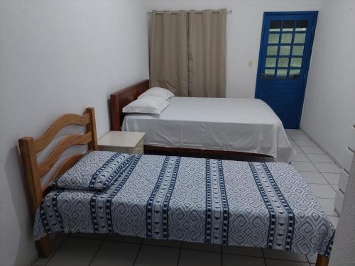 a bedroom with two beds and a blue door at CASA DA NINA in Tamandaré