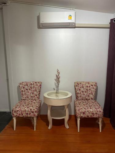 two chairs and a table with a vase on top of it at S Villa @Impact Muangthongthani in Pak Kret