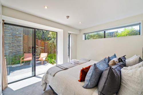 a bedroom with a bed and a sliding glass door at Hana Apartment by Sotheby's Luxury Rental Homes in Wanaka
