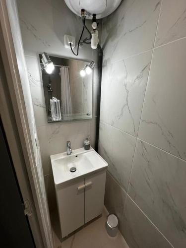 W białej łazience znajduje się umywalka i lustro. w obiekcie Maison Cosy w mieście Montauban