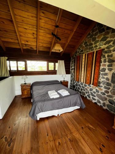 ein Schlafzimmer mit einem Bett und einer Steinmauer in der Unterkunft Cabañas Las Tahonas in Azul
