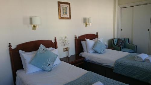 a hotel room with two beds with blue pillows at 17 Wilmington Square in Eastbourne