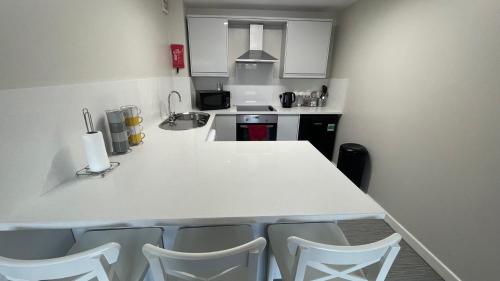 a kitchen with a white counter and chairs in it at Hosted By Ryan - 2 Bedroom Apartment in Liverpool