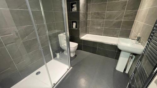 a bathroom with a shower and a toilet and a sink at Hosted By Ryan - 2 Bedroom Apartment in Liverpool