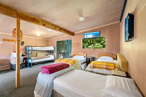 Un dormitorio con tres camas y un televisor. en Kings Drive - Wanaka Holiday Home, en Wanaka