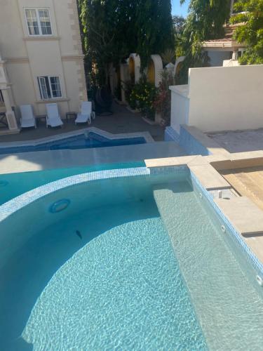a blue swimming pool in front of a house at Mandela Court Suites Grenada in Lance aux Épines
