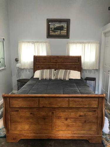 1 cama grande de madera en un dormitorio con 2 ventanas en Downtown Yellowstone Bungalow en Livingston