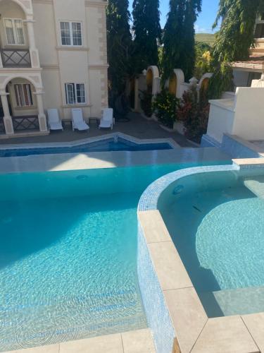 a swimming pool in front of a house at Mandela Court Suites Grenada in Lance aux Épines