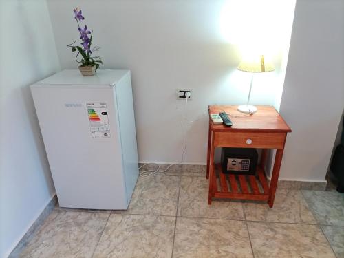 a white refrigerator next to a table with a lamp at Hotel Village del Sol in Puerto Iguazú