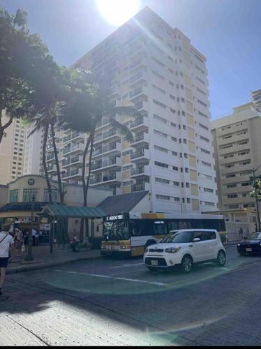 a bus parked in a parking lot in front of a building at Lovely Condo 2 Bedrooms, 2 bathrooms, free 1 Parking at Waikiki Beach in Honolulu