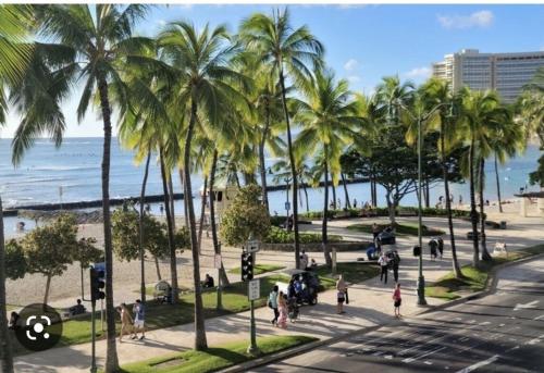 a group of people walking on a sidewalk near the beach at Lovely Condo 2 Bedrooms, 2 bathrooms, free 1 Parking at Waikiki Beach in Honolulu