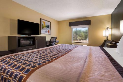 a hotel room with a large bed with a flat screen tv at Best Western Bradbury Inn & Suites in Perry