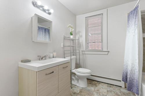 Baño blanco con aseo y lavamanos en Frog Hollow Red Door Retreat, en Hartford